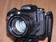 a camera sitting on top of a wooden table next to a brown cloth covered wall