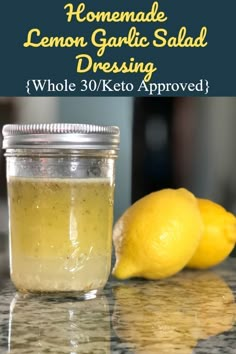 homemade lemon garlic salad dressing in a glass jar next to two lemons