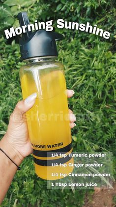 a woman holding up a yellow water bottle with the words morning sunshine on it in front of her face