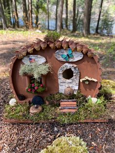 a fairy garden house made out of wood and clay with plants in the front yard