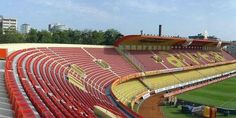 an empty stadium filled with lots of red and yellow seating chairs on top of a green field