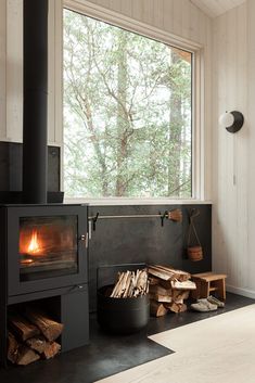 a wood burning stove in the corner of a room next to a pile of firewood