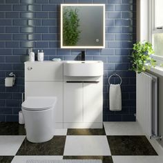 a white toilet sitting next to a bathroom sink under a mirror on a blue tiled wall