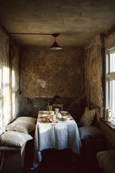 an old room with a table and two chairs in front of a window that has sunlight streaming through the windows