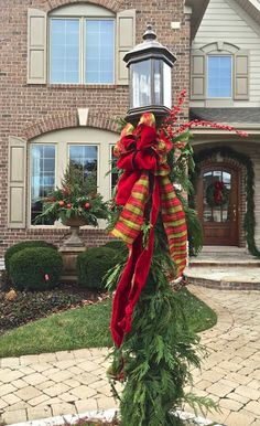 a christmas wreath on top of a pole in front of a house with a lamp post