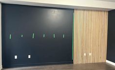 an empty room with black walls and wooden slats on the wall, in front of a sliding door