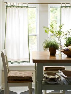 a dining room table with two chairs and a potted plant on the window sill