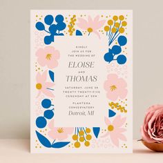 a pink and blue floral wedding card on a table