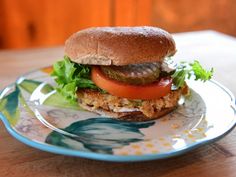 a sandwich with lettuce, tomato and onion on a bun sitting on a plate