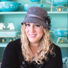 a woman wearing a hat sitting in front of shelves