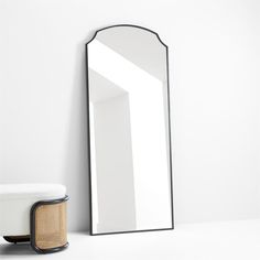 a mirror sitting on top of a white counter next to a stool and table lamp