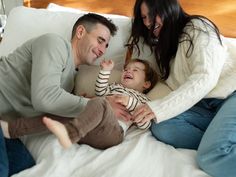 a man, woman and child laying on a bed