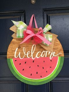 a watermelon welcome sign hanging on a door with a pink bow and green checkered ribbon