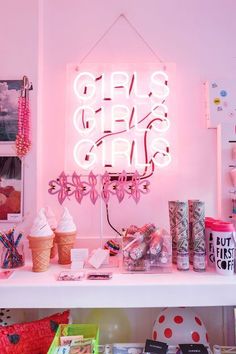 a pink neon sign that says girls's girls on it next to ice cream cones and other items