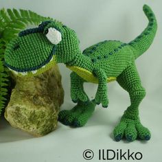 a green toy dinosaur next to a rock