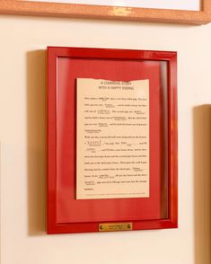 a red frame with a piece of paper hanging on the wall next to a framed letter