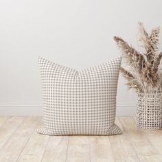 two pillows sitting next to each other on top of a wooden floor in front of a white wall