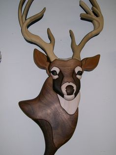 a wooden deer head mounted to the side of a wall