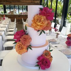 a three tiered cake with flowers on the top and sides, sitting on a table