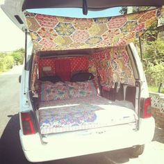 the back end of a white van with a bed in it