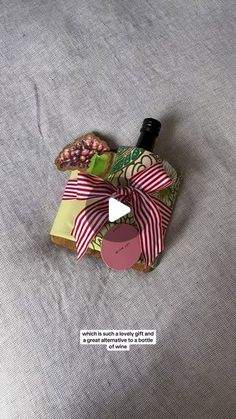 a bottle with a bow on it sitting on top of a bed next to a pillow