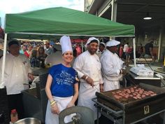 some people are standing near a grill with food on it and one person is wearing a chef's hat