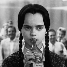 a woman with braids drinking from a bottle in front of a group of people