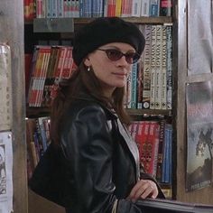 a woman standing in front of a bookshelf holding a book case and looking at the camera