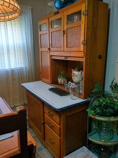 a kitchen with wooden cabinets and white counter tops next to a dining room table in front of a window