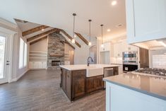 a large kitchen with an island in the middle and wood beams on the ceiling above it