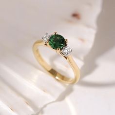 an emerald and diamond ring on a white background