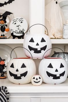 three pumpkins sitting on top of a white shelf next to other halloween decorations and dishes