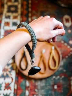 a person's hand holding onto a black beaded bracelet on top of a rug