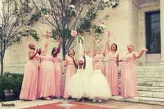 a group of women in pink dresses standing next to each other on the steps outside