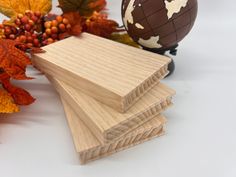 three pieces of wood sitting on top of each other next to leaves and a globe