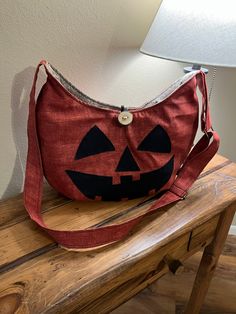 "This pumpkin bag is sure to conjure up the Halloween spirit in every outfit it's added to. Wear it facing out for a jack-o-lantern styled night or facing in for a less Halloween-ish and more fall-ish look! Handmade crossbody bag. Rust orange durable canvas fabric handbag with adjustable strap. Strap measures 24\" to 48\" and can be worn as a crossbody bag or shoulder purse. Beige upholstery fabric interior with 6 inside pockets. Constructed with a deep rust orange canvas outer. Bag measures: 16 Fall Hobo Bag With Adjustable Strap, Everyday Halloween Tote Bag, Halloween Shoulder Bag Gift, Halloween Shoulder Bag For Daily Use, Halloween Gift Shoulder Bag, Halloween Satchel Shoulder Bag With Adjustable Strap, Everyday Tote Bag For Halloween, Halloween Travel Crossbody Bag, Halloween Gift Crossbody Bag