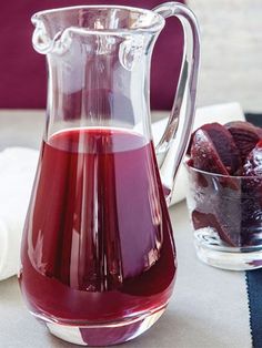 a pitcher filled with red liquid next to a glass bowl full of beetroot