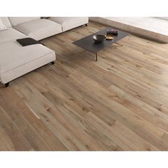 a living room with wood flooring and a couch in the corner, next to a coffee table