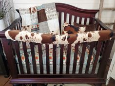 a brown and white cow print baby crib bedding set with pillows on it