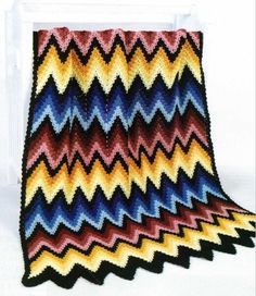 a crocheted blanket with multicolored zigzag pattern on it