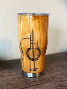 a wooden cup sitting on top of a table next to a white wall with a guitar drawn on it