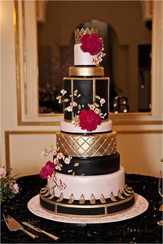 a three tiered cake with red flowers on the top and gold trimmings