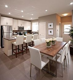 a kitchen and dining room with an island in the middle, white chairs around it