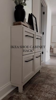 a white cabinet sitting in the middle of a living room next to a mirror and door