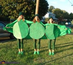 two women dressed in green are standing on the grass