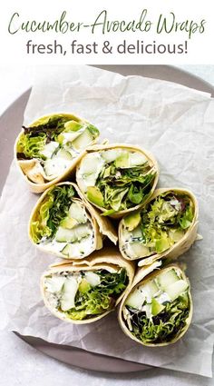 several wraps filled with lettuce, cheese and other toppings on top of a white plate