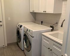 a washer and dryer in a small room with white cabinets on the walls