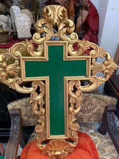 an ornate gold and green cross sitting on top of a wooden chair in a room