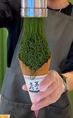 a person is holding an ice cream cone with green grass in it