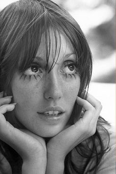 a black and white photo of a woman with freckles on her face looking at the camera